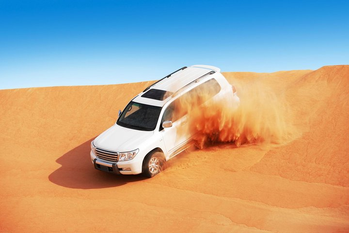Experience the excitement of dune bashing in a 4x4 racing across the stunning sands of Dubai's desert where adventure meets unforgettable moments under the endless azure sky.